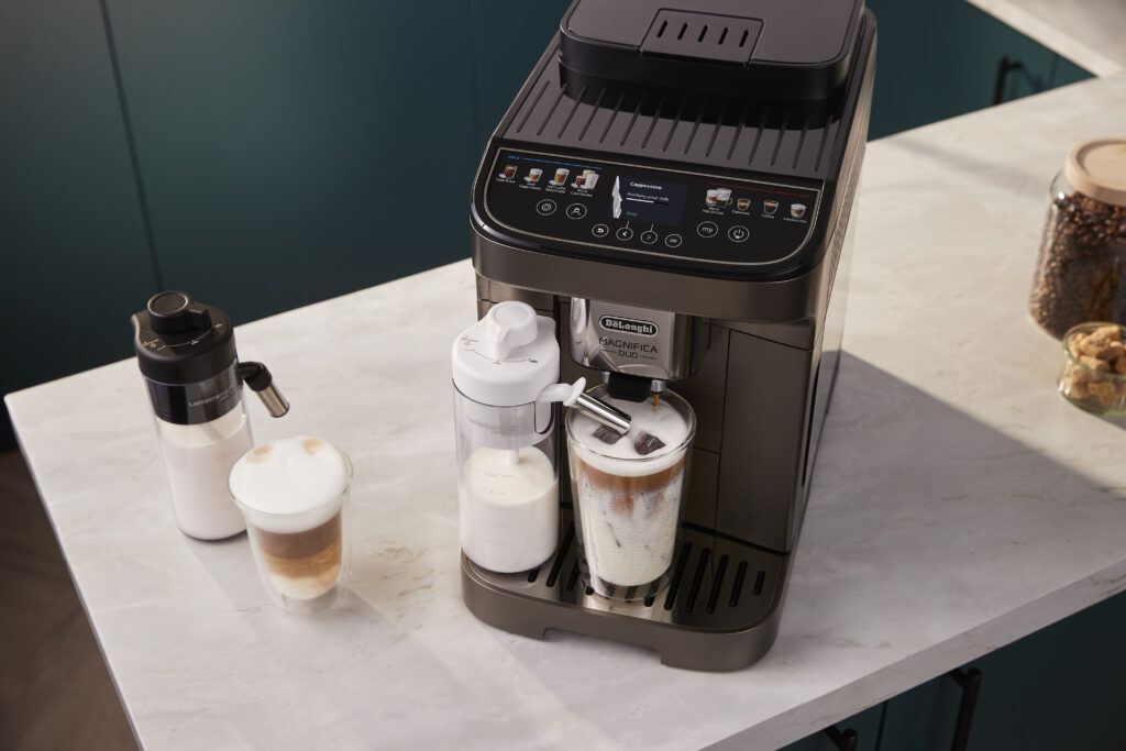 Black automatic espresso machine with milk frother making iced latte on marble countertop